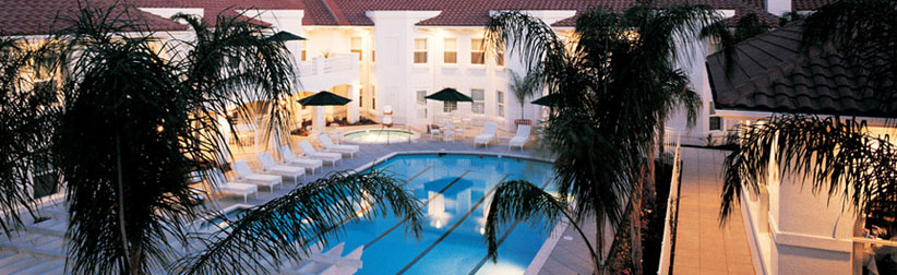 Aerial shot of beautiful building, pool, and lawn chairs at sunset